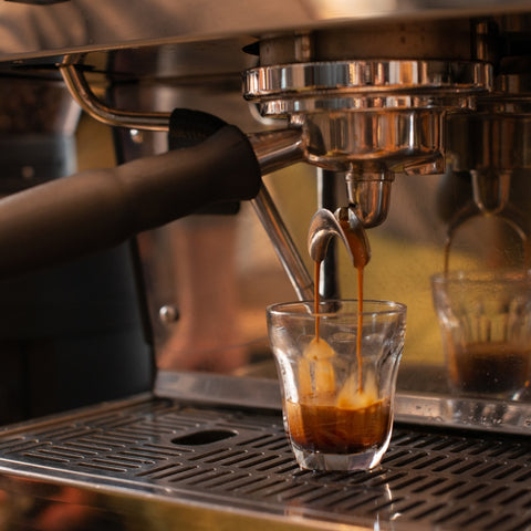 Espresso being poured from a machine into a glass.