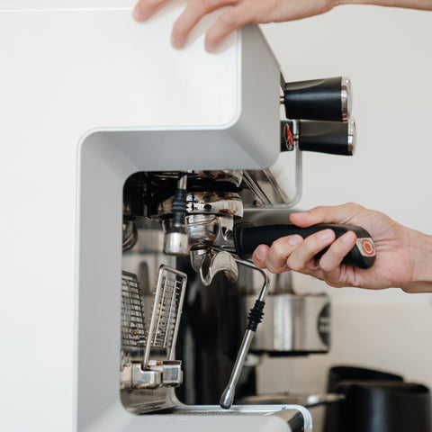 Person using an espresso machine with a white background