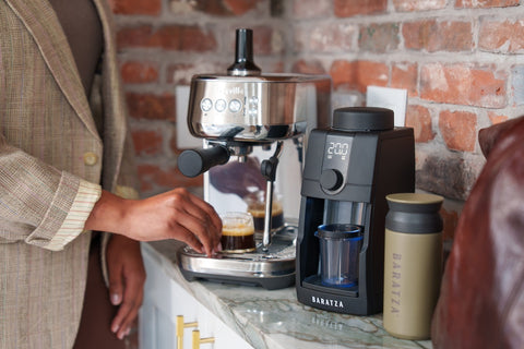 Person using a Baratza coffee grinder with a brick wall background
