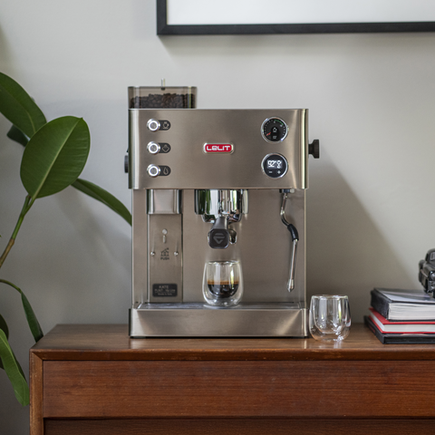 Lelit Kate espresso machine on a wooden surface with a plant and books in the background
