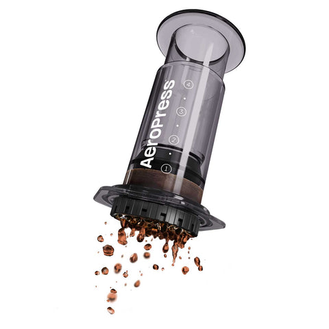 Aeropress coffee maker with ground coffee spilling out on a white background