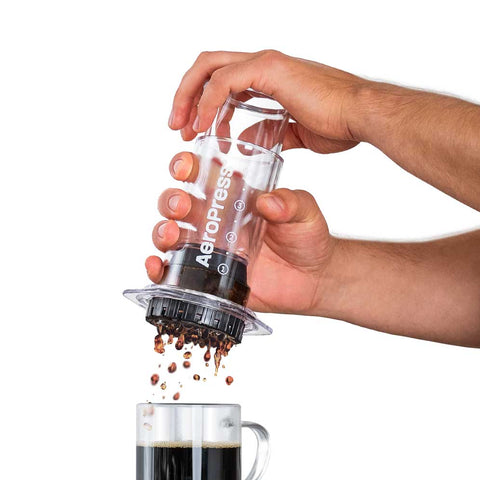 Person using an Aeropress to make coffee with a white background