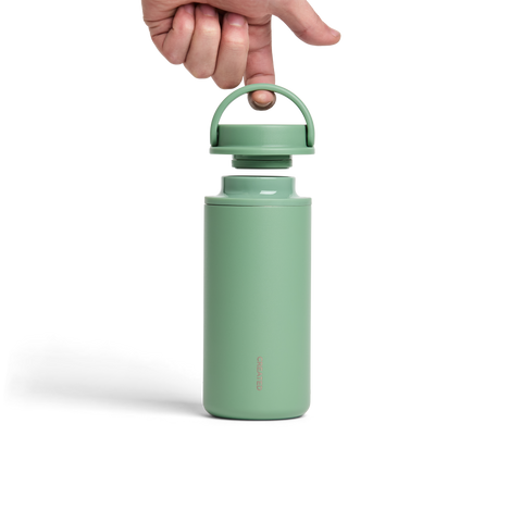 Green water bottle with a handle being held by a hand on a white background