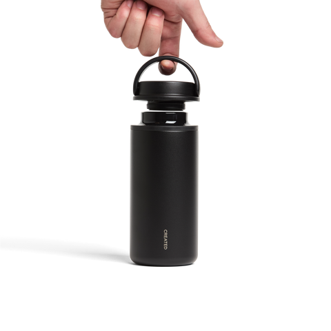 Black water bottle with a hand opening the lid on a white background