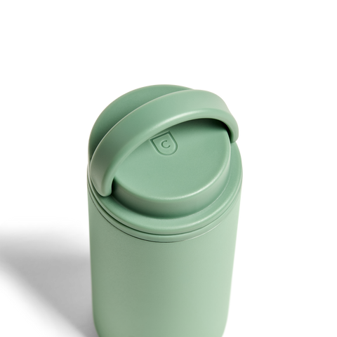 Green travel mug with a lid on a white background