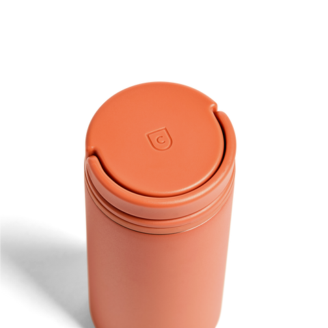 Terracotta-colored tumbler with a lid on a white background