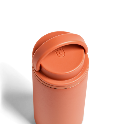 Terracotta-colored tumbler with a lid on a white background