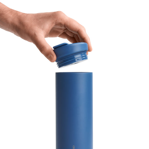 Hand placing a blue lid on a blue cylindrical container against a white background