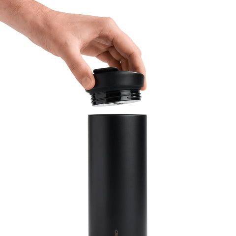Hand placing a black lid on a black cylindrical object against a white background