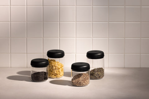 Fellow Atmos Vacuum Canister Five glass jars with black lids on a tiled wall background