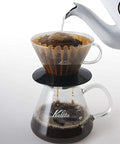 Coffee brewing process using a Kalita Wave 185 Glass Dripper  and glass carafe on a white background