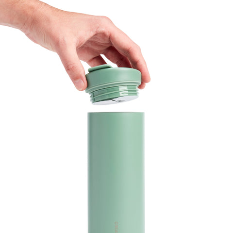 Hand placing a green lid on a green water bottle against a white background