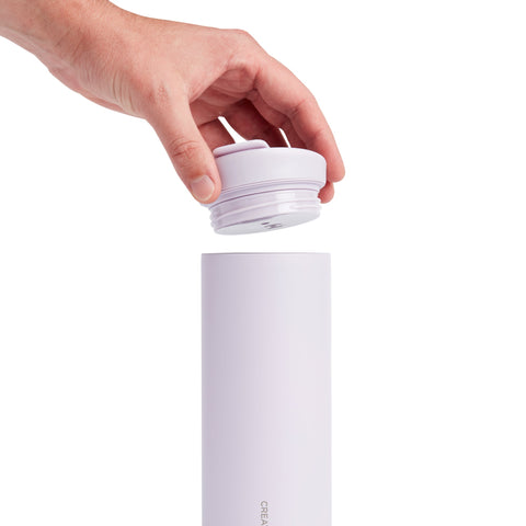 Hand placing a white cap on a cylindrical product with 'Ceramic' branding.