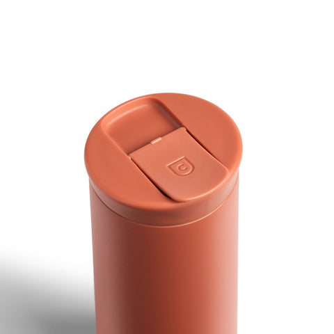 Terracotta-colored tumbler with a lid on a white background