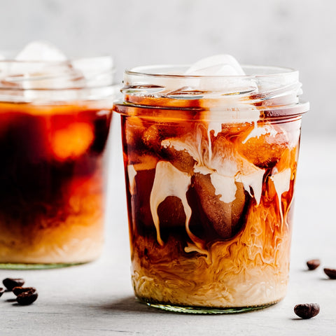 Two glasses of iced coffee with a white background