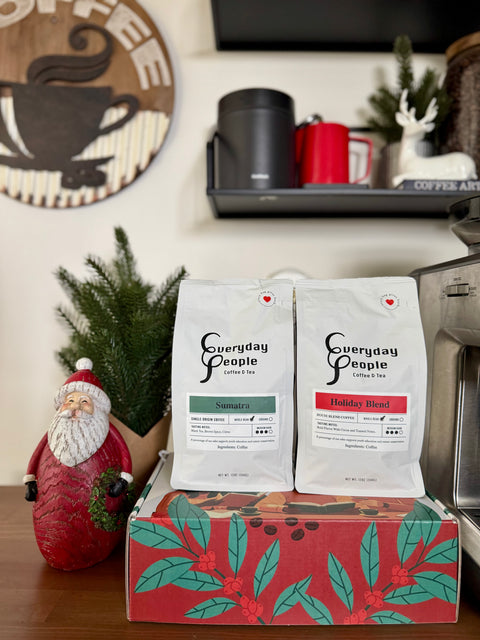 Two coffee bags labeled 'Everyday People' on a decorative box with a Santa Claus figurine and coffee-themed decor in the background.