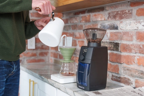 Person using a coffee grinder with a brick wall background