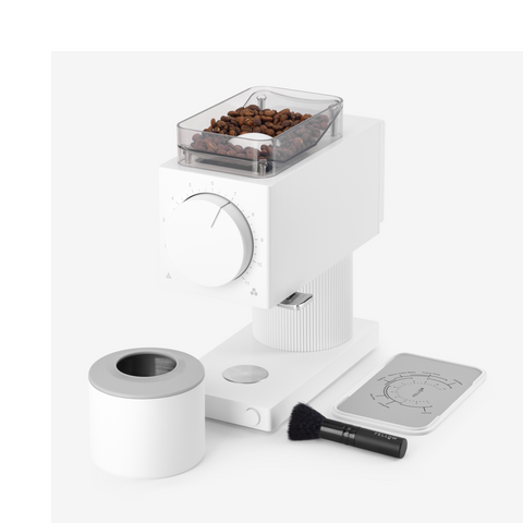 White coffee grinder with beans, cleaning brush, and scale on a white background