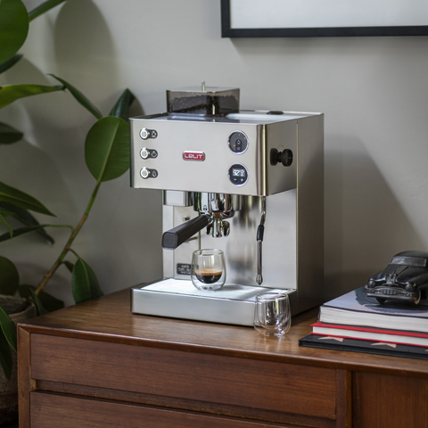 Lelit Kate espresso machine on a wooden surface with a plant and books in the background