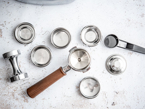 Collection of metal coffee tampers and lids on a light surface