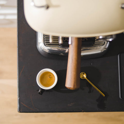 Ascaso Dream PID Automatic Home Espresso Machine - Sweet Cream with a cup of espresso and a spoon on a black surface.