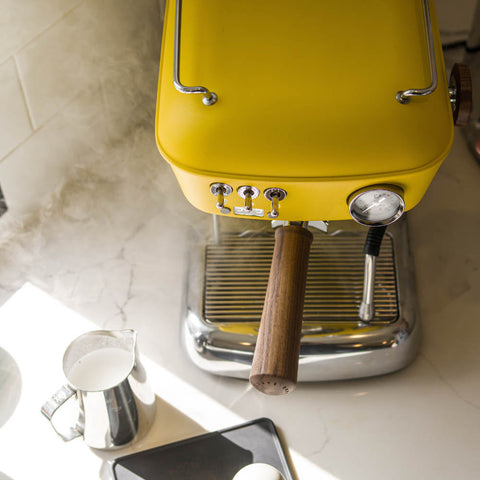 Ascaso Dream PID Automatic Home Espresso Machine - Sun Yellow on a marble countertop with a milk pitcher and phone.