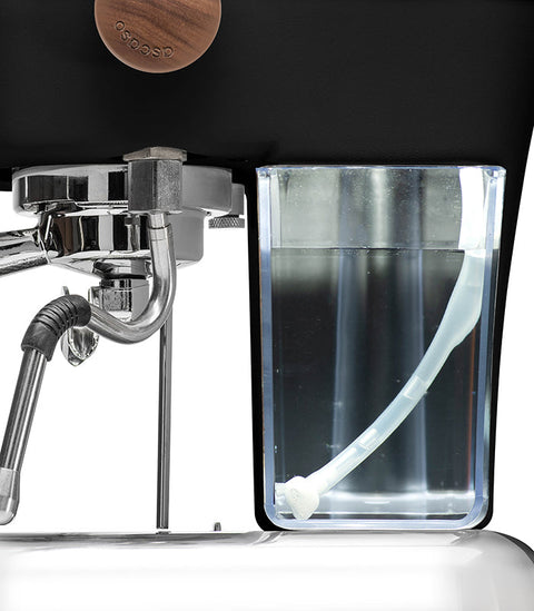 Ascaso Dream PID Automatic Home Espresso Machine - Dark Black with a clear container attached, likely for water or milk, on a dark background.
