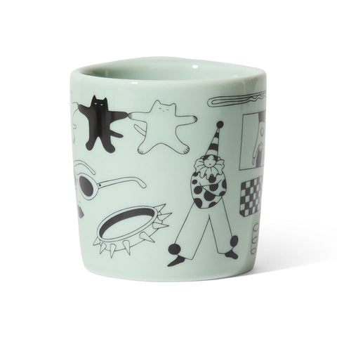 Light green ceramic mug with black line art illustrations on a white background