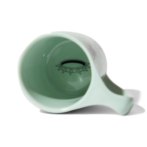 Light green ceramic mug with a unique design on a white background