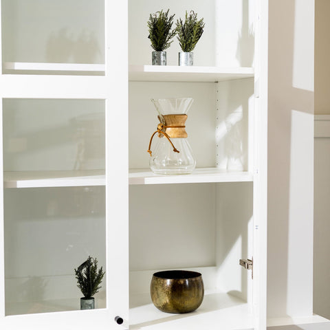 White shelving unit with decorative items including a Chemex coffee maker and small plants.