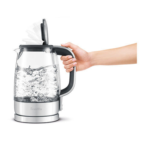 Breville electric kettle being held with water boiling inside, on a white background