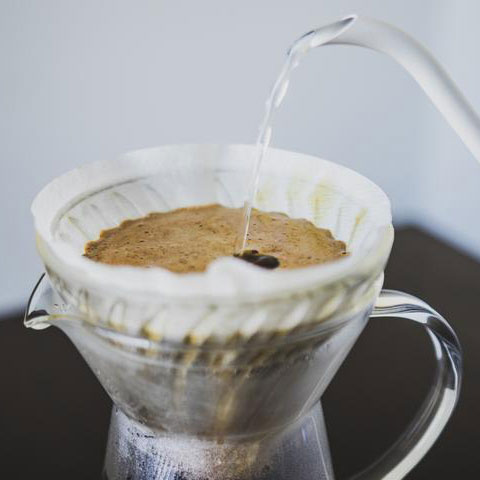 Coffee being poured into a filter with a white background