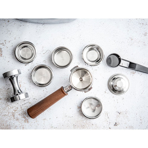 Collection of metal coffee tampers and lids on a textured white surface
