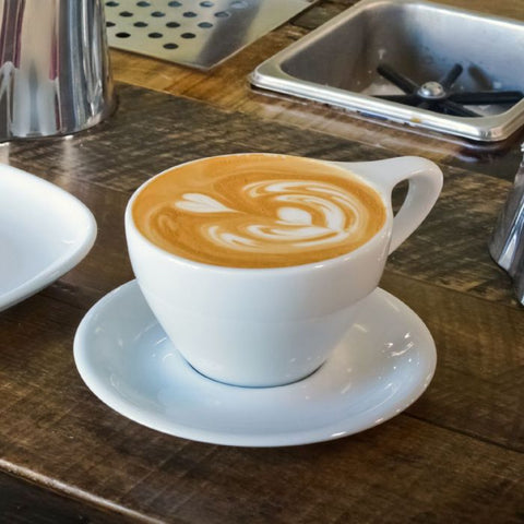 Cappuccino in a white cup on a wooden counter