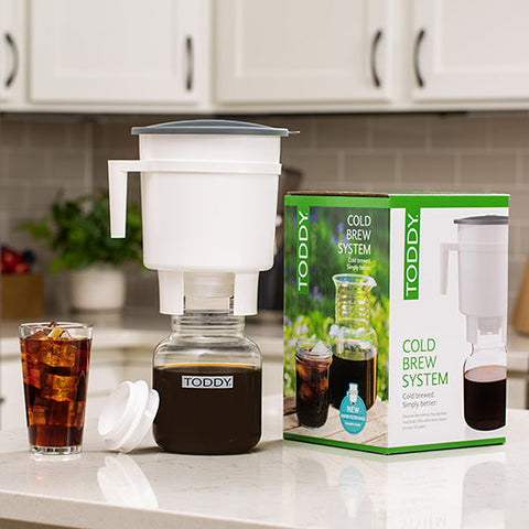 Toddy cold brew system on a kitchen counter with a glass of iced coffee.