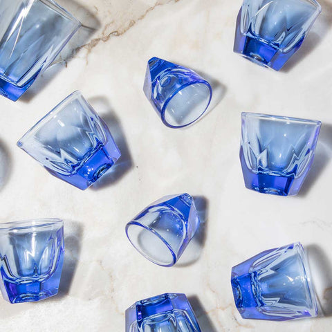 Blue glass shot glasses on a light stone surface