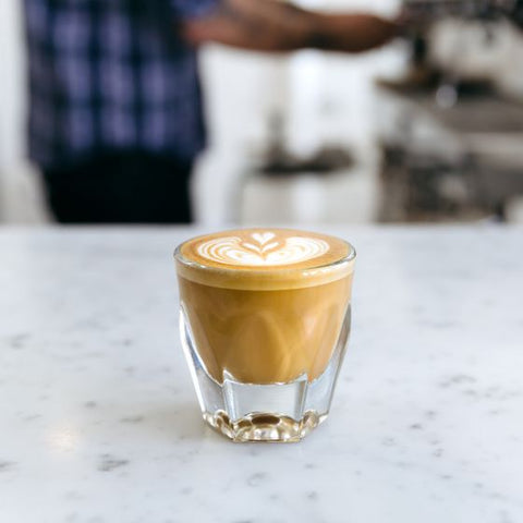 Cappuccino in a glass on a marble surface with a blurred background