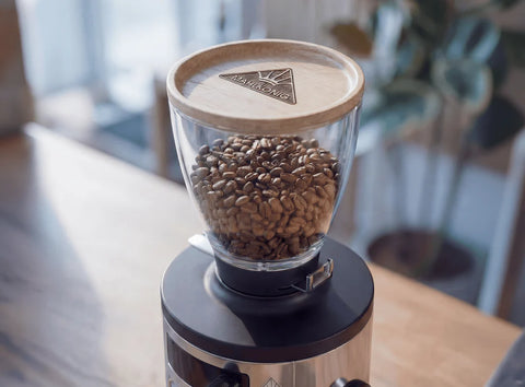 Mahlkönig X54 Allround Home Grinder coffee grinder with coffee beans on a wooden table